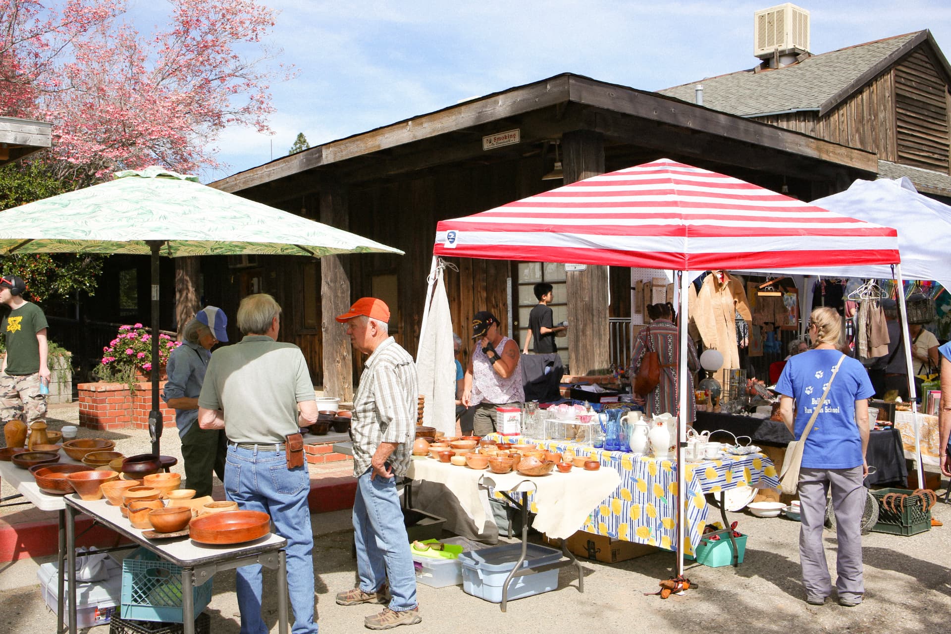 Shoppers browsing hand-turned wooden bowls and glassware under striped canopies outside the Fruit Exchange Building.