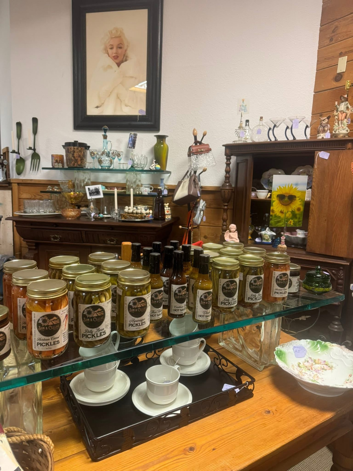 Jars of local pickles and hot sauces on a glass shelf at The Colfax Bazaar.