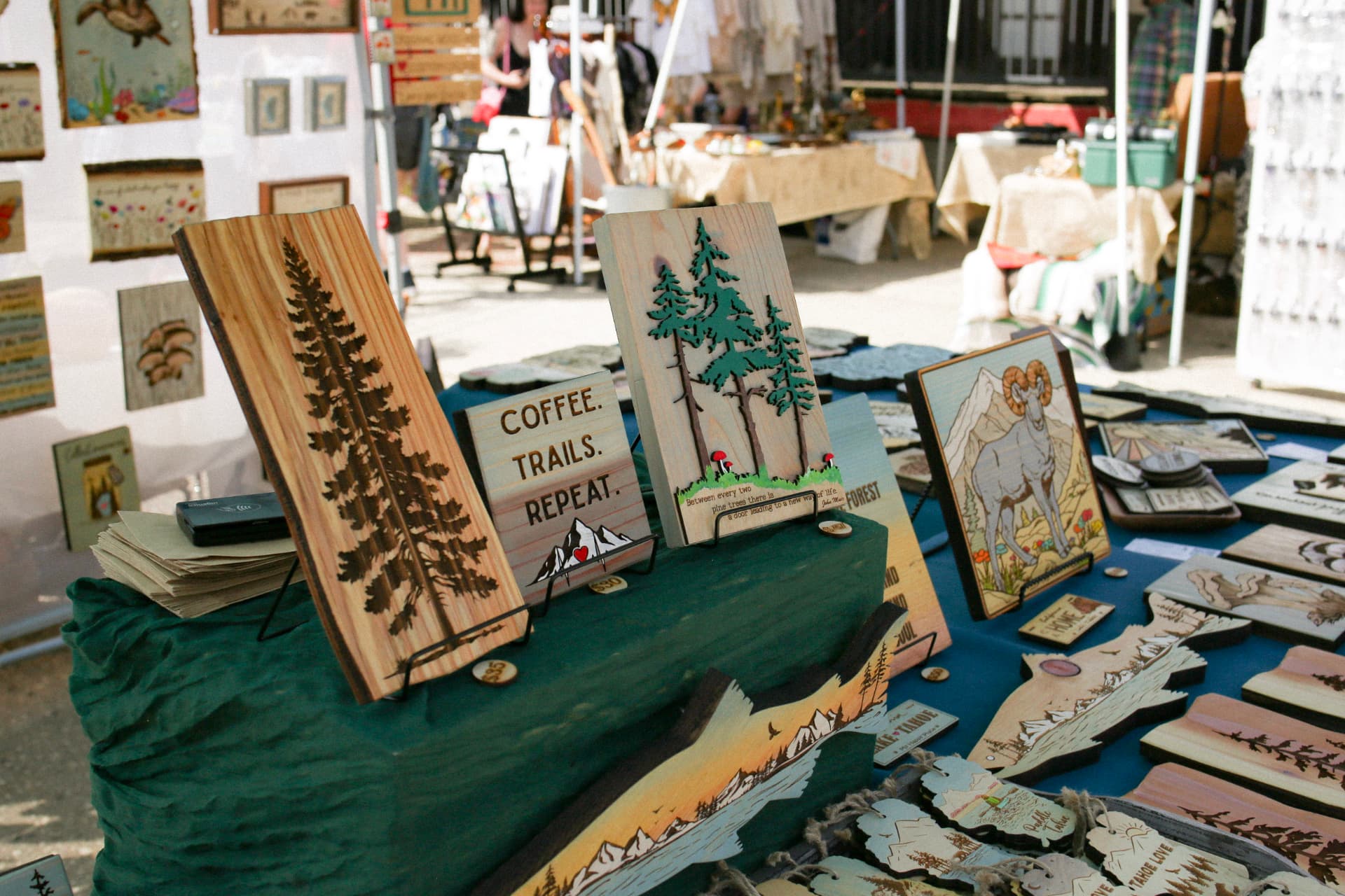 Laser-cut and engraved wooden Sierra Nevada signs and art at a maker's booth.