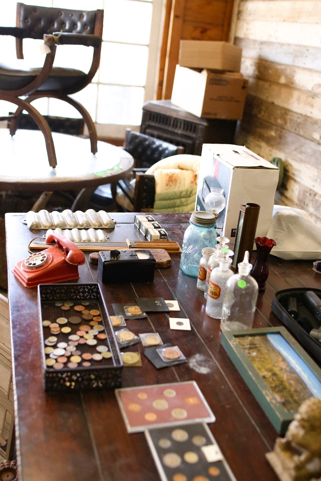 A table of antiques inside the Fruit Exchange Building: a red rotary phone, coins, and glass bottles.