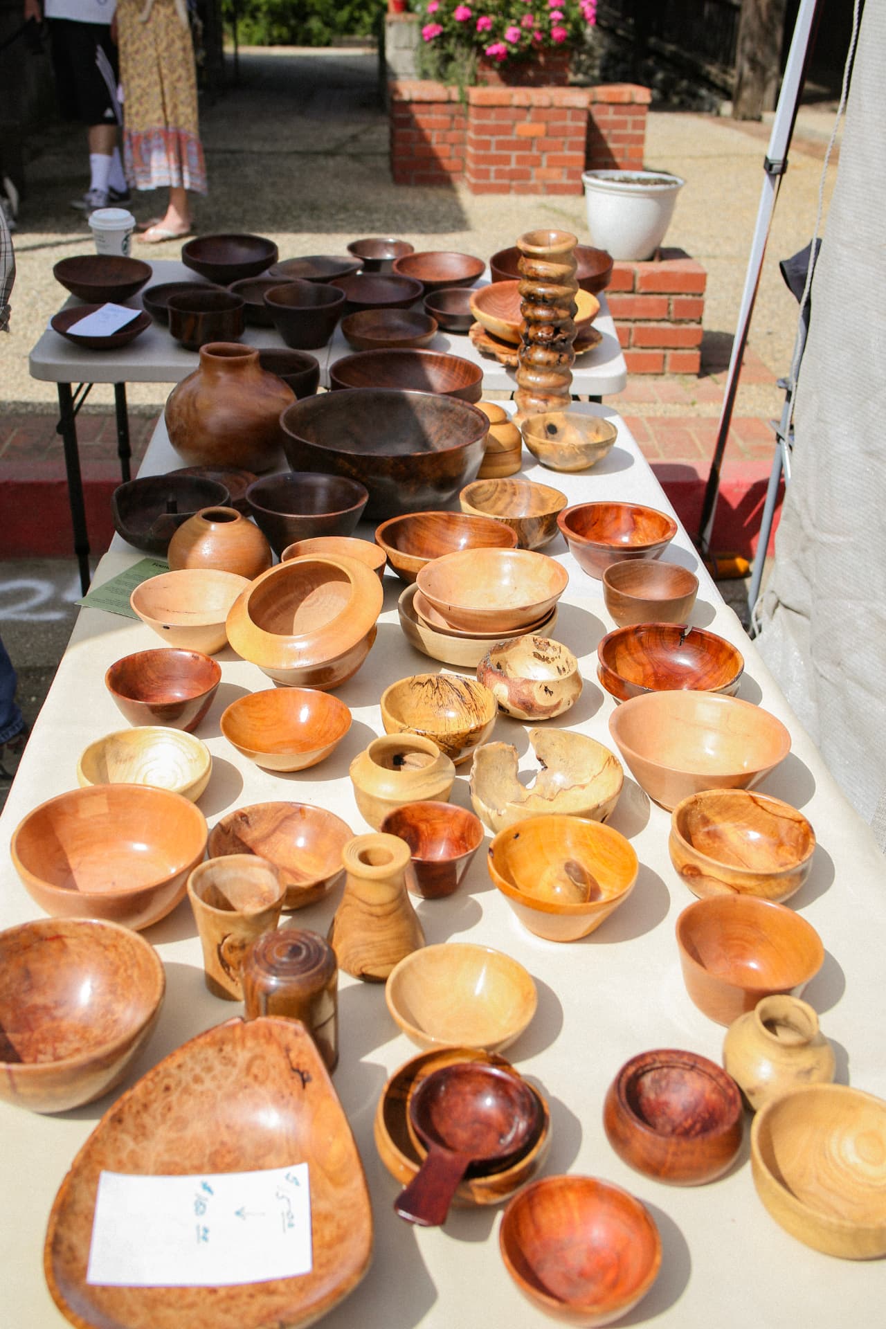 Dozens of hand-turned wooden bowls and vessels displayed on a maker's table.